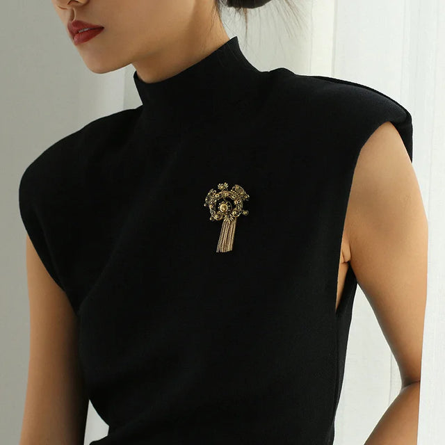 Black sleeveless top with a decorative brooch worn by a person.