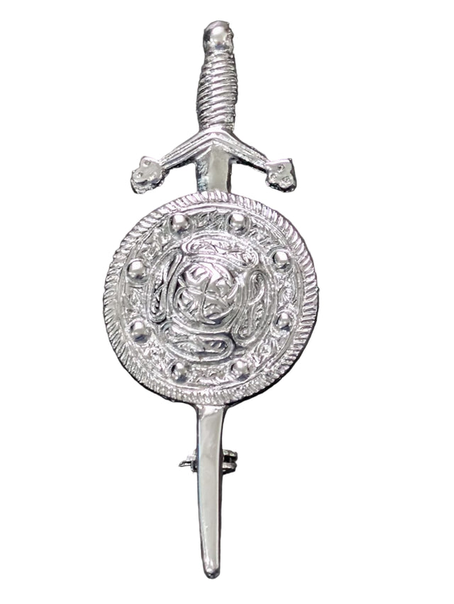 Silver kilt pin with decorative design on a gray surface