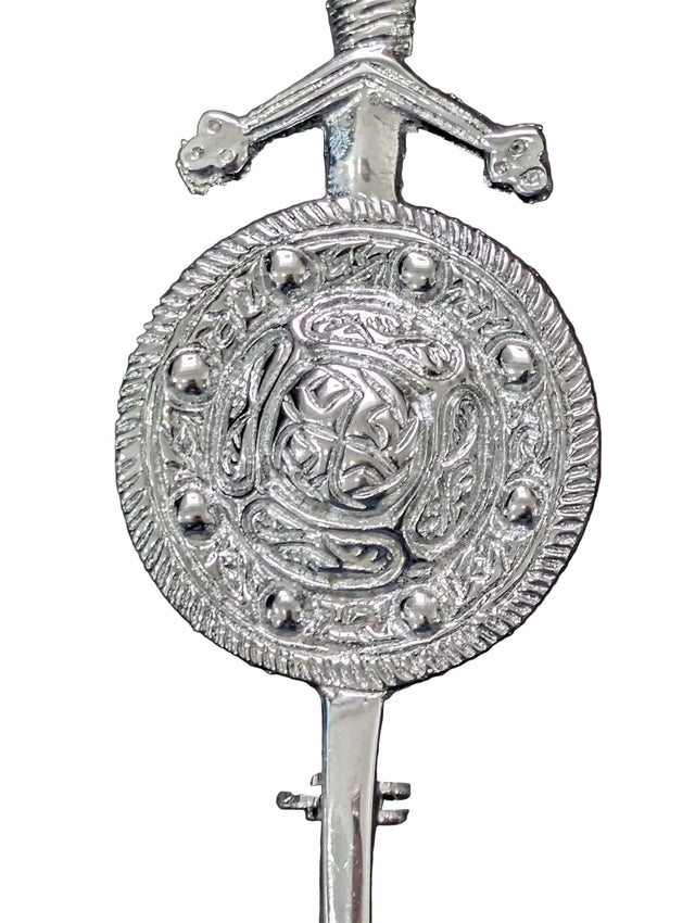 Decorative silver key with intricate design on a dark background