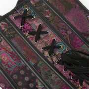 Close-up of a patchwork corset top with colorful paisley and floral fabric panels, black faux-leather trim, and black laces threaded through silver eyelets.