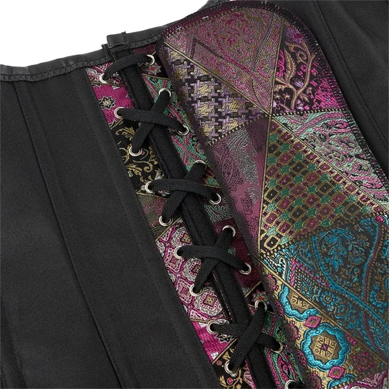 Close-up of a black corset with a colorful patchwork paisley lining, featuring black laces threaded through silver metal eyelets.