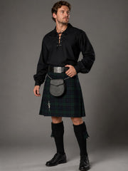 Man wearing a black shirt, green kilt, and black shoes against a gray background