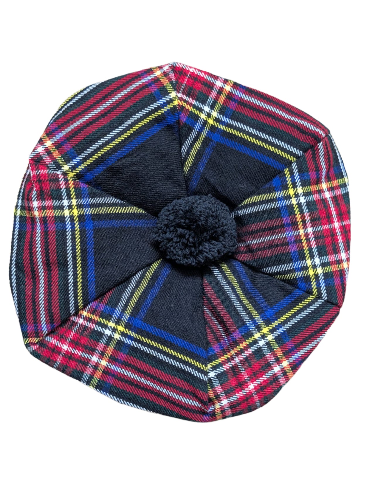 Plaid hat with a central black pom-pom on a wooden surface