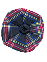 Plaid hat with a central black pom-pom on a wooden surface