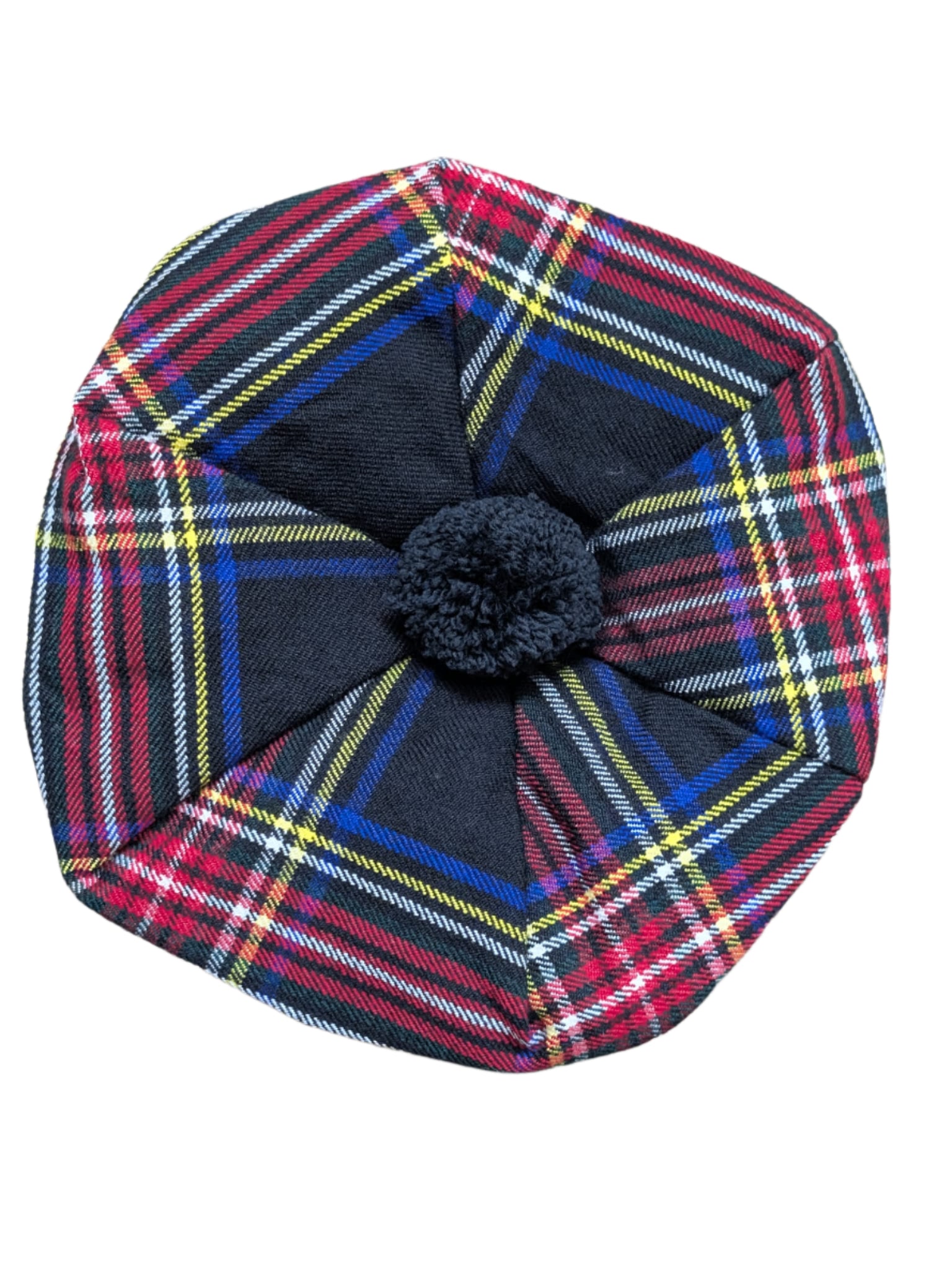Plaid hat with a central black pom-pom on a wooden surface