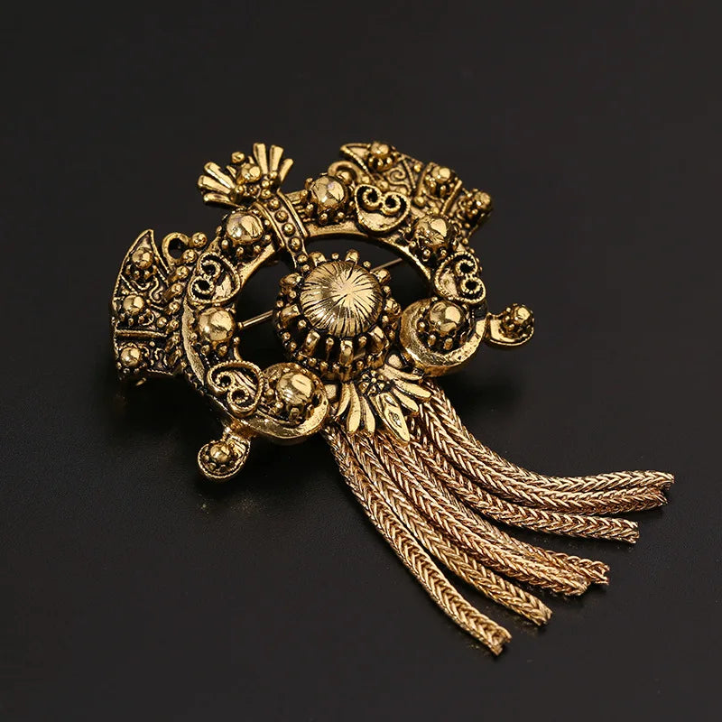 Decorative gold brooch with intricate design on a black background