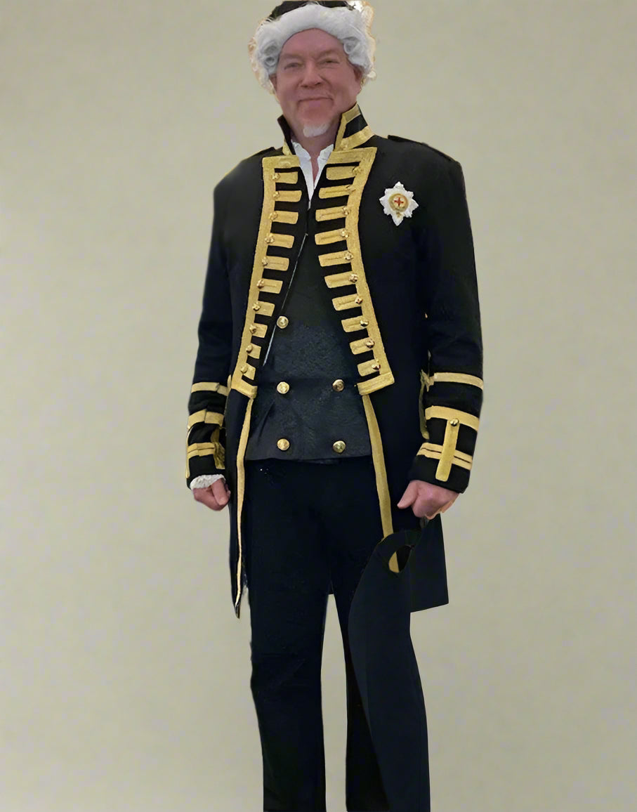 Man in formal attire with decorative elements in a room with other people.