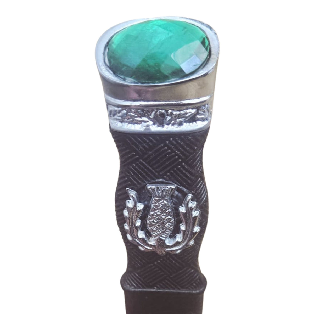 Decorative object with a green gemstone and silver emblem on a white background