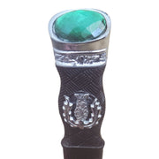 Decorative object with a green gemstone and silver emblem on a white background