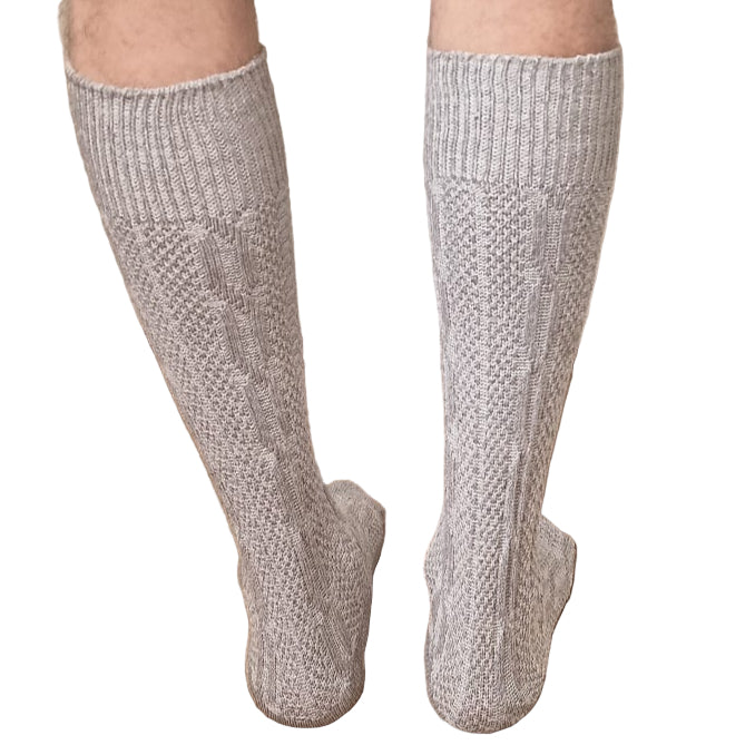 Person wearing gray knee-high socks on a wooden floor.
