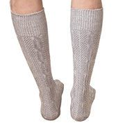 Person wearing gray knee-high socks on a wooden floor.